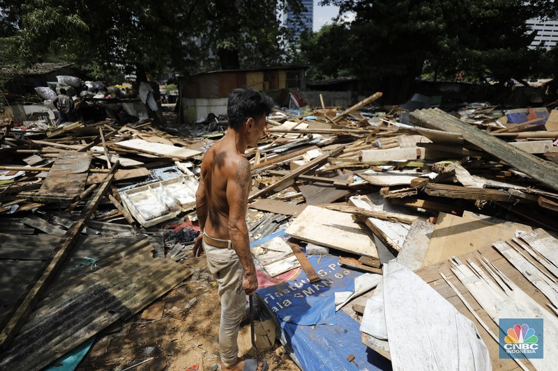 Seorang warga beraktivitas di lokasi puing-puing rumah semi permanen di TPU Menteng Pulo, Jakarta, Jumat (12/12/2025). (CNBC Indonesia/Tri Susilo)