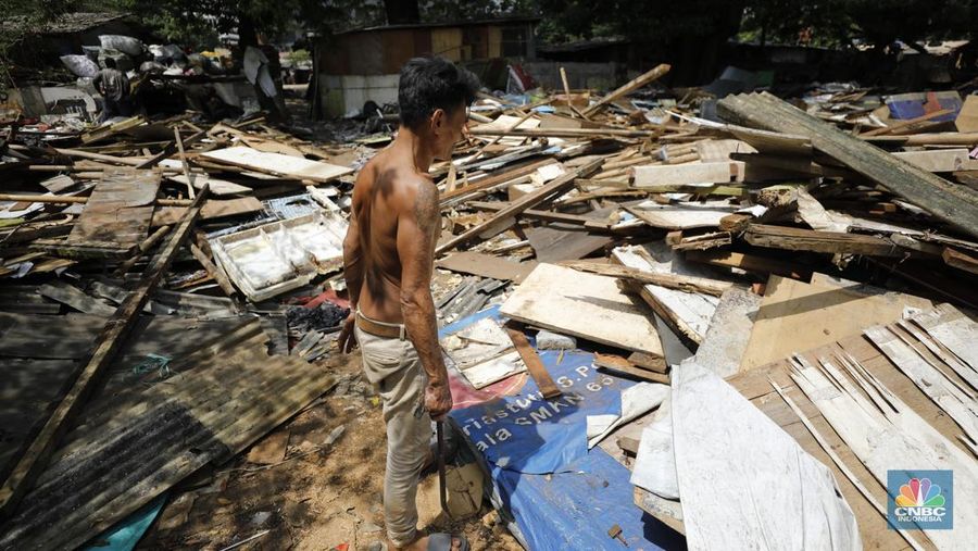 Seorang warga beraktivitas di lokasi puing-puing rumah semi permanen di TPU Menteng Pulo, Jakarta, Jumat (12/12/2025). (CNBC Indonesia/Tri Susilo)