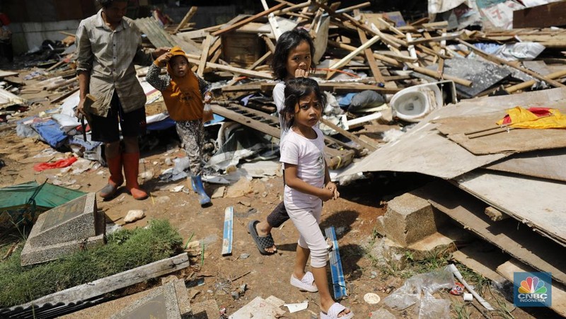 Seorang warga beraktivitas di lokasi puing-puing rumah semi permanen di TPU Menteng Pulo, Jakarta, Jumat (12/12/2025). (CNBC Indonesia/Tri Susilo)