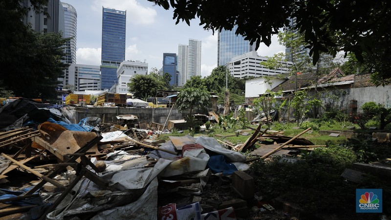 Seorang warga beraktivitas di lokasi puing-puing rumah semi permanen di TPU Menteng Pulo, Jakarta, Jumat (12/12/2025). (CNBC Indonesia/Tri Susilo)