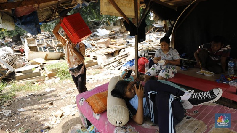 Seorang warga beraktivitas di lokasi puing-puing rumah semi permanen di TPU Menteng Pulo, Jakarta, Jumat (12/12/2025). (CNBC Indonesia/Tri Susilo)