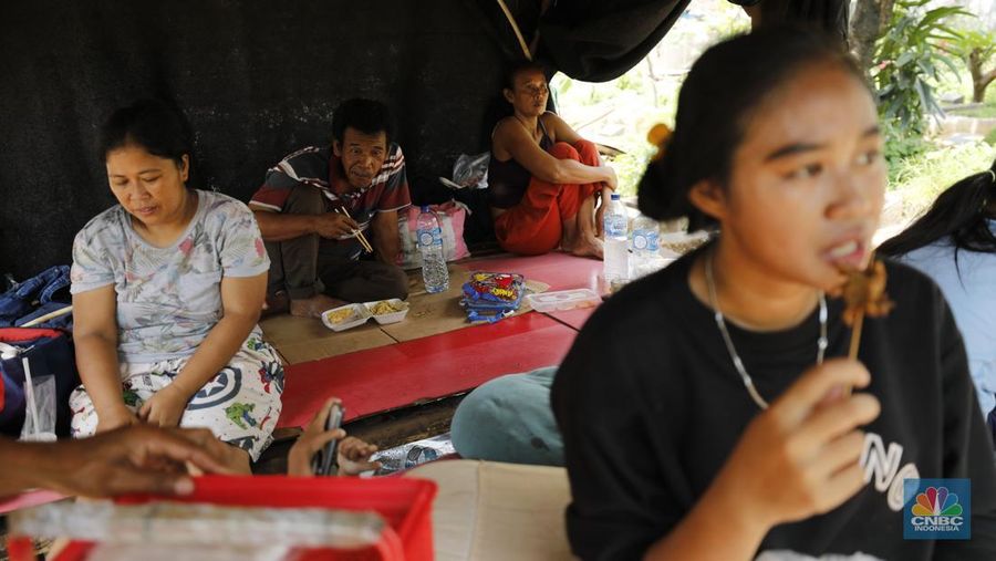 Seorang warga beraktivitas di lokasi puing-puing rumah semi permanen di TPU Menteng Pulo, Jakarta, Jumat (12/12/2025). (CNBC Indonesia/Tri Susilo)