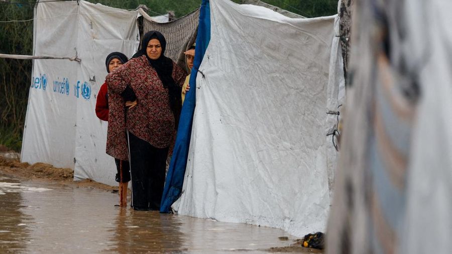 Seorang pria Palestina pengungsi membersihkan air berlumpur di kamp tenda yang tergenang banjir pada hari hujan di Nuseirat, Jalur Gaza tengah, 12 Desember 2025. (REUTERS/Mahmoud Issa)