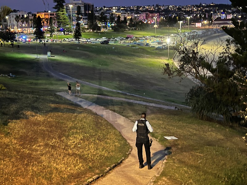 Cuplikan layar dari video ini memperlihatkan pemandangan udara dari tubuh-tubuh yang tertutup kain dan darah di tanah, sebuah kendaraan dengan pintu terbuka, dan polisi di lokasi kejadian penembakan di Pantai Bondi di Sydney, Australia, 14 Desember 2025. (NINE NETWORK/SEVEN NETWORK/AUSTRALIAN BROADCASTING CORPORATION/Handout via REUTERS)