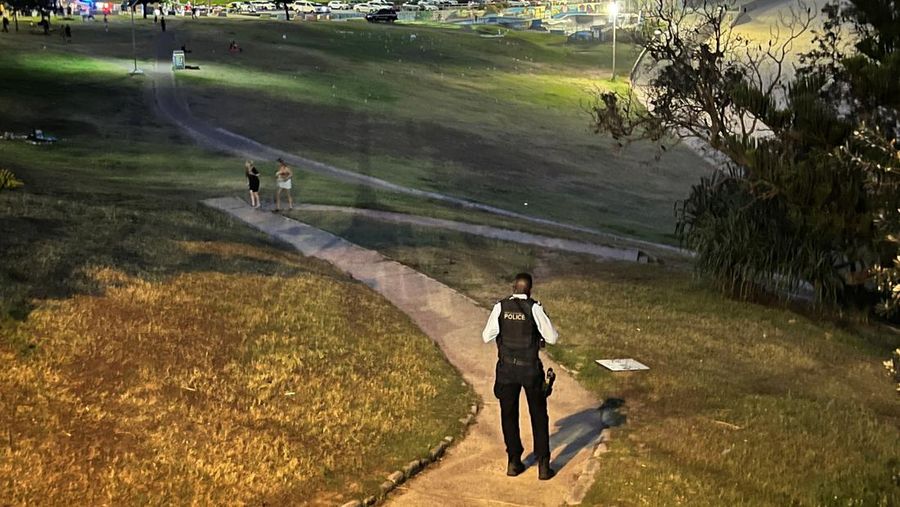 Cuplikan layar dari video ini memperlihatkan pemandangan udara dari tubuh-tubuh yang tertutup kain dan darah di tanah, sebuah kendaraan dengan pintu terbuka, dan polisi di lokasi kejadian penembakan di Pantai Bondi di Sydney, Australia, 14 Desember 2025. (NINE NETWORK/SEVEN NETWORK/AUSTRALIAN BROADCASTING CORPORATION/Handout via REUTERS)