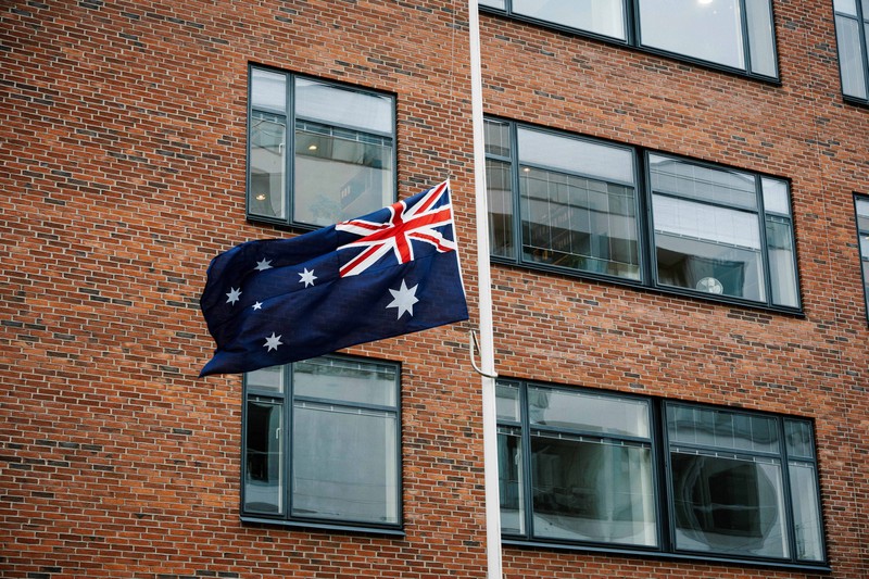 Australia mengibarkan bendera setengah tiang usai penembakan massal di Pantai Bondi yang menewaskan 11 orang, Senin (15/12/2025). Bendera setengah tiang sebagai bentuk duka cita nasional. (via REUTERS/Emil Nicolai Helms)