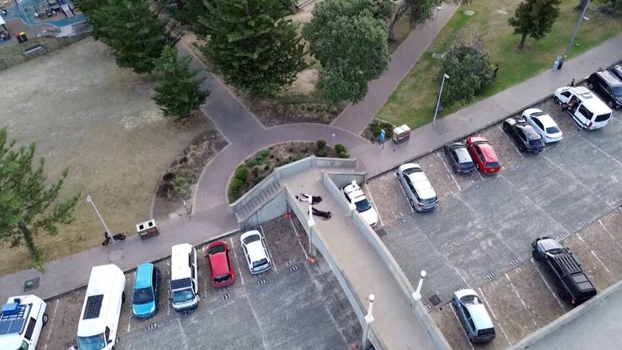 Sebuah tayangan drone menunjukkan salah satu tersangka pelaku penembakan di jembatan penyeberangan, di samping tersangka pelaku penembakan lainnya yang sedang berbaring, sementara para korban tergeletak di tanah, setelah insiden penembakan di Pantai Bondi, Sydney, Australia, 14 Desember 2025, dalam cuplikan layar yang diperoleh dari video media sosial. (@bonusik28 via X/via REUTERS)