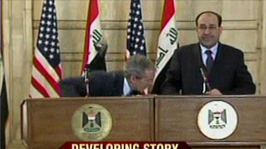 Cuplikan dari video siaran langsung, yang diperoleh CNN, menunjukkan Presiden AS George W. Bush (latar belakang kiri), menunduk saat seorang jurnalis melemparkan dua sepatu ke arahnya pada 14 Desember 2008 dalam kunjungan perpisahan Bush ke Irak. (Photo by CNN / AFP/File Foto)