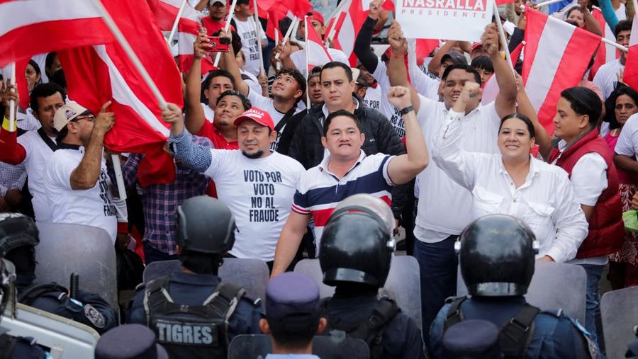 Para pendukung calon presiden Salvador Nasralla dari Partai Liberal berunjuk rasa di depan polisi anti huru hara, lebih dari dua minggu setelah pemilihan presiden, karena penghitungan suara masih terhenti di tengah surat suara yang belum dihitung, tuduhan kecurangan, dan kegagalan sistem pemilu, di Tegucigalpa, Honduras, 15 Desember 2025. (REUTERS/Fredy Rodriguez)