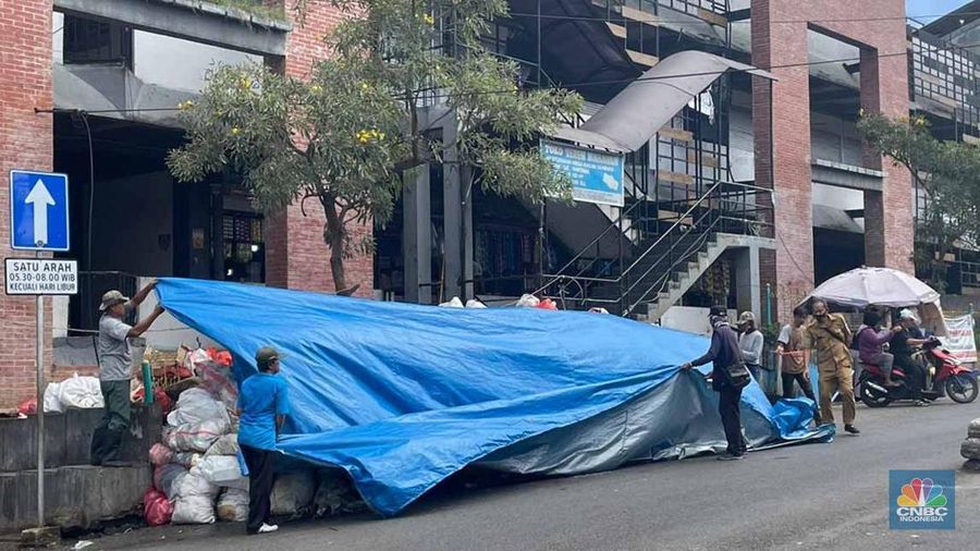 Sejumlah kendaraan melintas di antara tumpukan sampah yang berserakan di beberapa titik Pasar Ciputat, Kebayoran Lama, Selasa (16/12/2025). (CNBC Indonesia/Romys Binekasri)