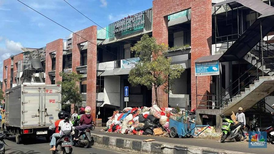 Sejumlah kendaraan melintas di antara tumpukan sampah yang berserakan di beberapa titik Pasar Ciputat, Kebayoran Lama, Selasa (16/12/2025). (CNBC Indonesia/Romys Binekasri)