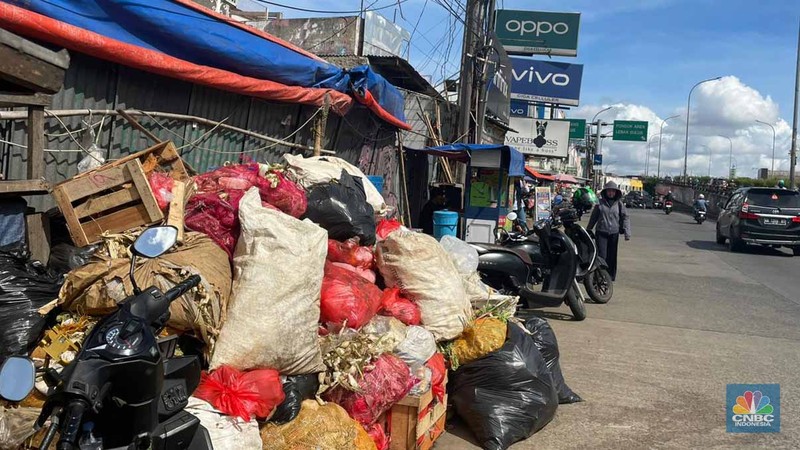 Sejumlah kendaraan melintas di antara tumpukan sampah yang berserakan di beberapa titik Pasar Ciputat, Kebayoran Lama, Selasa (16/12/2025). (CNBC Indonesia/Romys Binekasri)