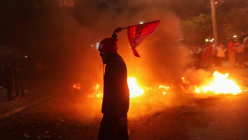Para pendukung calon presiden Salvador Nasralla dari Partai Liberal berunjuk rasa di depan polisi anti huru hara, lebih dari dua minggu setelah pemilihan presiden, karena penghitungan suara masih terhenti di tengah surat suara yang belum dihitung, tuduhan kecurangan, dan kegagalan sistem pemilu, di Tegucigalpa, Honduras, 15 Desember 2025. (REUTERS/Fredy Rodriguez)