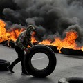Seorang pendukung pemerintah menggulirkan ban di samping penghalang jalan yang terbakar hampir dua minggu setelah pemilihan presiden, sementara penghitungan suara masih terhenti di tengah surat suara yang belum dihitung, tuduhan kecurangan, dan kegag