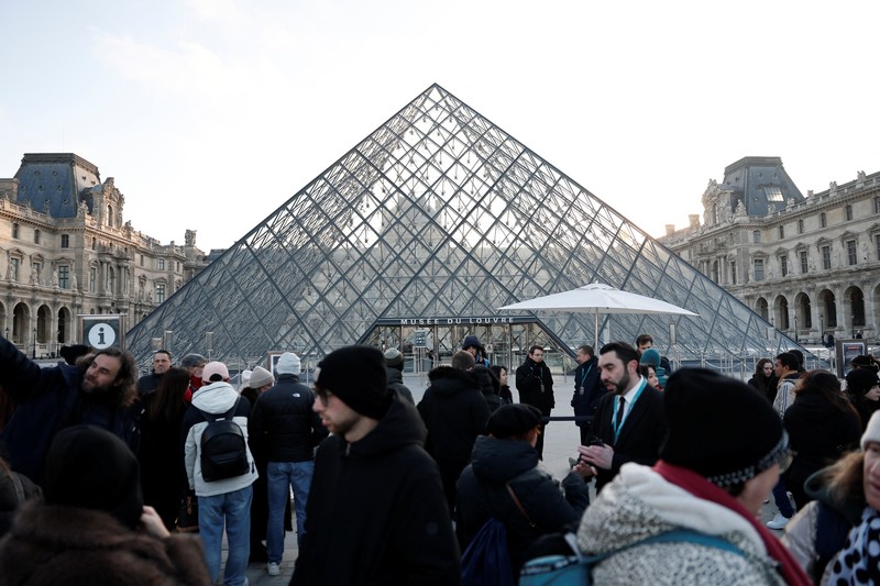 Ratusan turis terpaksa mengantre di luar Museum Louvre di Prancis pada Rabu (17/12/2025) waktu setempat. Jam buka museum tertunda imbas serikat pekerja menggelar pemungutan suara untuk melanjutkan aksi mogok kerja terkait kondisi kerja di museum ikonik tersebut. (REUTERS/Abdul Saboor)