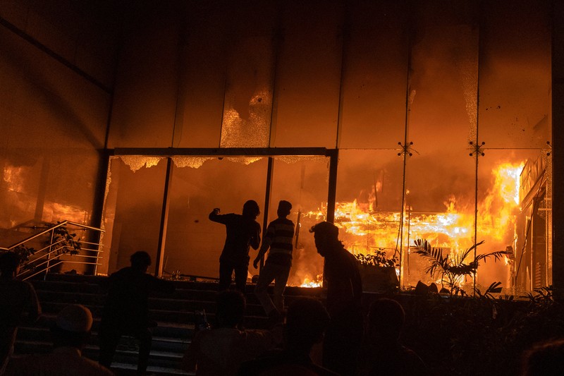 Seorang pria berjalan setelah sekelompok orang membakar gedung kantor surat kabar The Daily Star menyusul kematian Sharif Osman Hadi, seorang pemimpin mahasiswa yang sedang menjalani perawatan di Singapura setelah ditembak di kepala, di Dhaka, Bangladesh, 19 Desember 2025. (REUTERS/Abdul Goni)