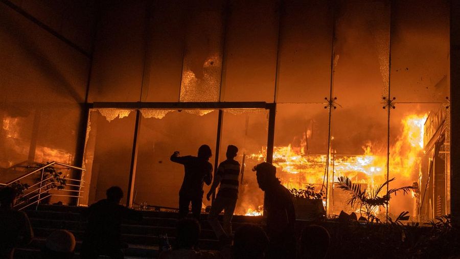 Seorang pria berjalan setelah sekelompok orang membakar gedung kantor surat kabar The Daily Star menyusul kematian Sharif Osman Hadi, seorang pemimpin mahasiswa yang sedang menjalani perawatan di Singapura setelah ditembak di kepala, di Dhaka, Bangladesh, 19 Desember 2025. (REUTERS/Abdul Goni)