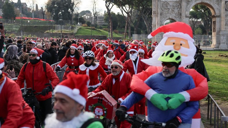 Sejumlah warga berdandan menjadi sinterklas dan bersepeda keliling Roma untuk menggalang dana untuk kegiatan amal, Minggu (21/12/2025). (REUTERS/Yara Nardi)