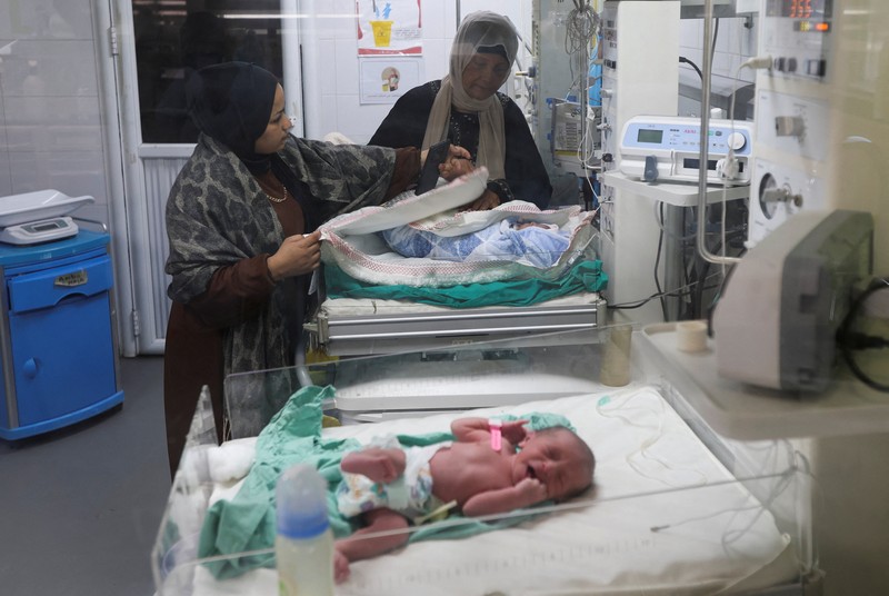 Palestinians pray near the body of baby Saeed Abdeen, who according to the medics died due to cold weather, in Khan Younis, southern Gaza Strip, December 18, 2025. REUTERS/Ramadan Abed