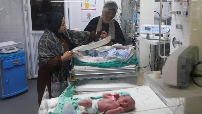 Palestinians pray near the body of baby Saeed Abdeen, who according to the medics died due to cold weather, in Khan Younis, southern Gaza Strip, December 18, 2025. REUTERS/Ramadan Abed