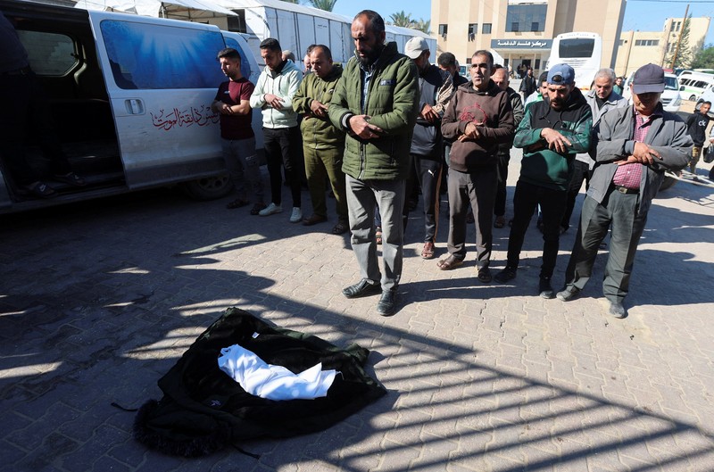 Palestinians pray near the body of baby Saeed Abdeen, who according to the medics died due to cold weather, in Khan Younis, southern Gaza Strip, December 18, 2025. REUTERS/Ramadan Abed