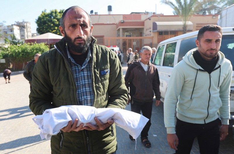 Palestinians pray near the body of baby Saeed Abdeen, who according to the medics died due to cold weather, in Khan Younis, southern Gaza Strip, December 18, 2025. REUTERS/Ramadan Abed