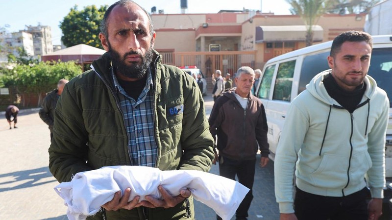 Palestinians pray near the body of baby Saeed Abdeen, who according to the medics died due to cold weather, in Khan Younis, southern Gaza Strip, December 18, 2025. REUTERS/Ramadan Abed