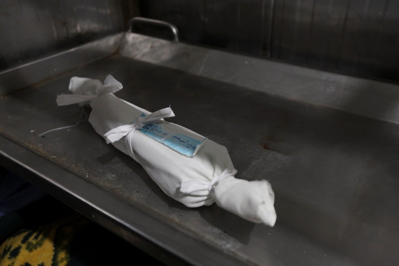 Palestinians pray near the body of baby Saeed Abdeen, who according to the medics died due to cold weather, in Khan Younis, southern Gaza Strip, December 18, 2025. REUTERS/Ramadan Abed