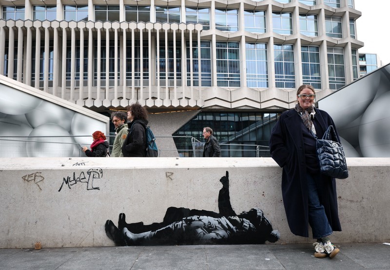 Seseorang berjalan melewati mural baru yang dilaporkan karya seniman anonim Banksy, di Tottenham Court Road, London, Inggris, 22 Desember 2025. (REUTERS/Isabel Infantes)