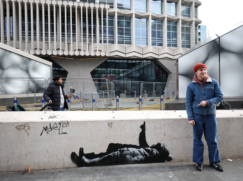 Seseorang berjalan melewati mural baru yang dilaporkan karya seniman anonim Banksy, di Tottenham Court Road, London, Inggris, 22 Desember 2025. (REUTERS/Isabel Infantes)