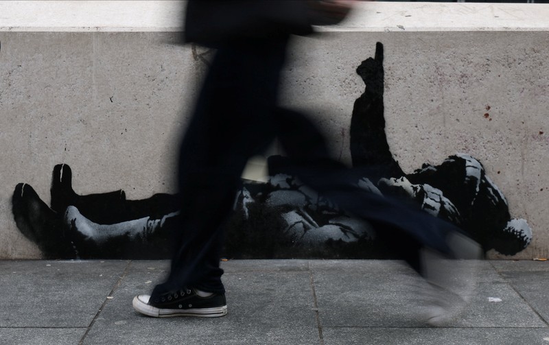 Seseorang berjalan melewati mural baru yang dilaporkan karya seniman anonim Banksy, di Tottenham Court Road, London, Inggris, 22 Desember 2025. (REUTERS/Isabel Infantes)