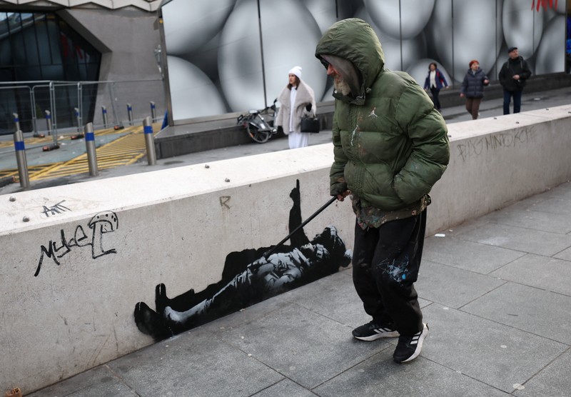 Seseorang berjalan melewati mural baru yang dilaporkan karya seniman anonim Banksy, di Tottenham Court Road, London, Inggris, 22 Desember 2025. (REUTERS/Isabel Infantes)