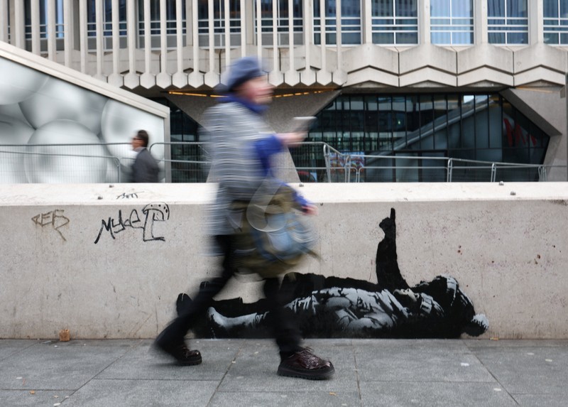 Seseorang berjalan melewati mural baru yang dilaporkan karya seniman anonim Banksy, di Tottenham Court Road, London, Inggris, 22 Desember 2025. (REUTERS/Isabel Infantes)