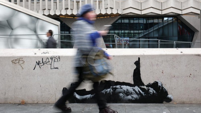 Seseorang berjalan melewati mural baru yang dilaporkan karya seniman anonim Banksy, di Tottenham Court Road, London, Inggris, 22 Desember 2025. (REUTERS/Isabel Infantes)