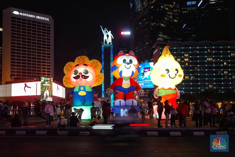 Warga melintas di antara aneka ornamen lampu hias dalam