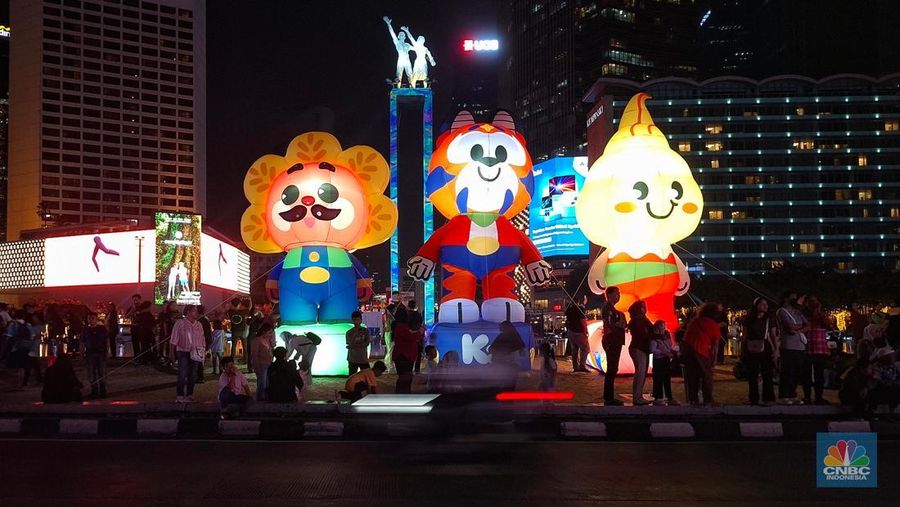 Warga melintas di antara aneka ornamen lampu hias dalam 