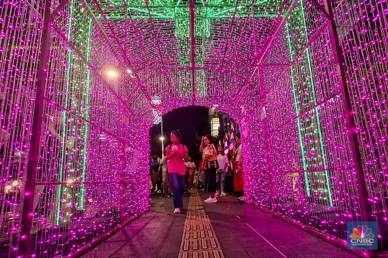 Warga melintas di antara aneka ornamen lampu hias dalam