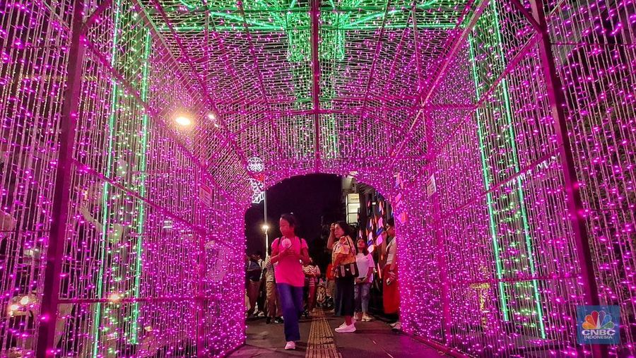 Warga melintas di antara aneka ornamen lampu hias dalam 