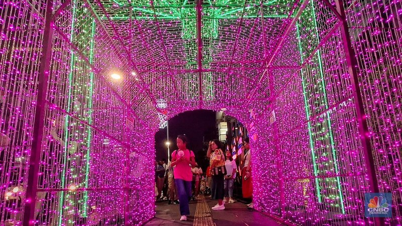 Warga melintas di antara aneka ornamen lampu hias dalam 