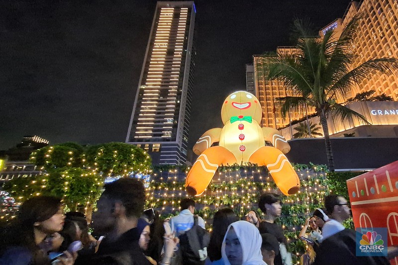 Warga melintas di antara aneka ornamen lampu hias dalam