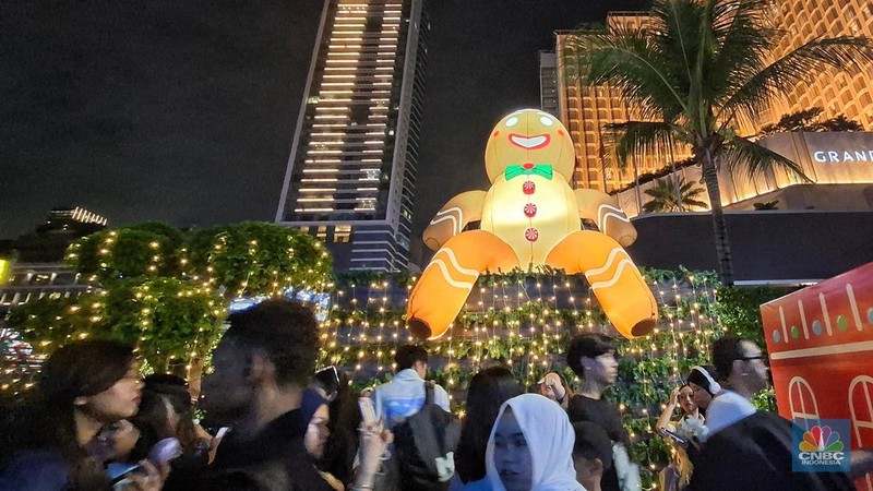 Warga melintas di antara aneka ornamen lampu hias dalam 