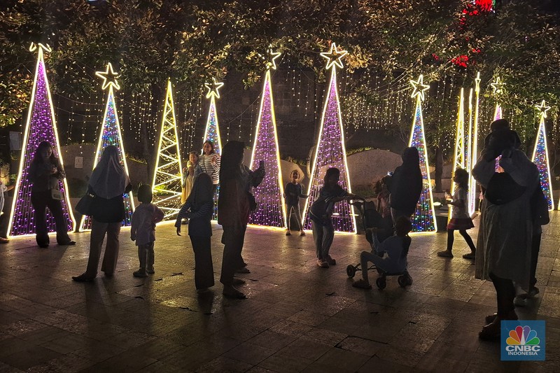 Warga melintas di antara aneka ornamen lampu hias dalam