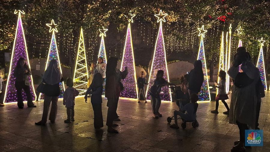 Warga melintas di antara aneka ornamen lampu hias dalam 