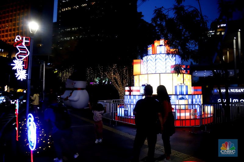 Warga melintas di antara aneka ornamen lampu hias dalam