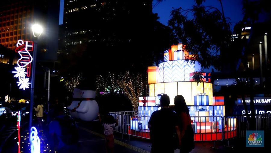 Warga melintas di antara aneka ornamen lampu hias dalam 