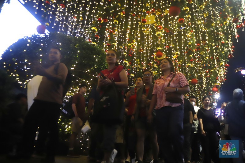 Warga melintas di antara aneka ornamen lampu hias dalam