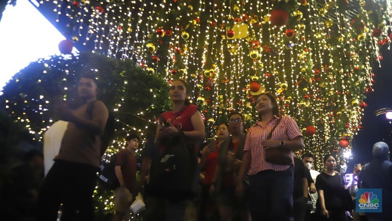 Warga melintas di antara aneka ornamen lampu hias dalam 
