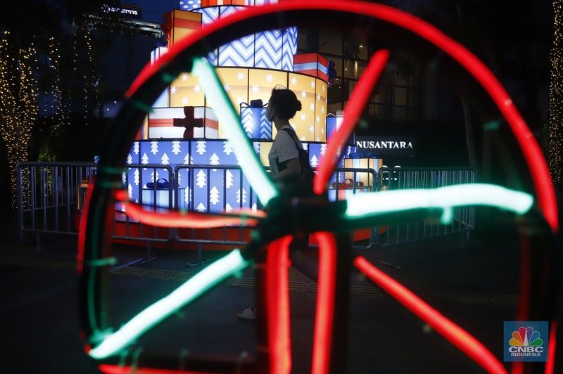 Warga melintas di antara aneka ornamen lampu hias dalam