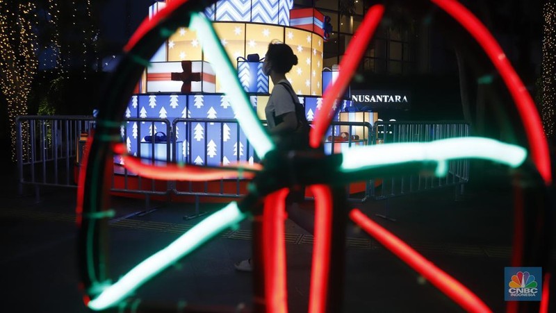 Warga melintas di antara aneka ornamen lampu hias dalam 