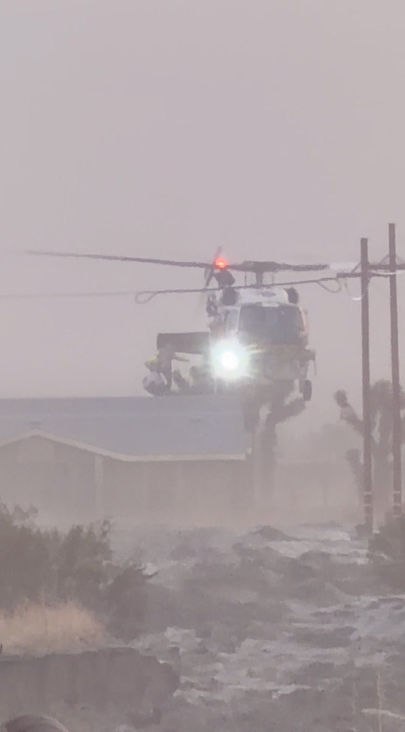 People sit on the roof of a building while they are stranded during floods partially submerging the surrounding area in the aftermath of torrential rains, in San Bernardino County, California, U.S. December 24, 2025 in this screengrab obtained from a social media video. Timothy and the Machine Music via Facebook/via REUTERS  THIS IMAGE HAS BEEN SUPPLIED BY A THIRD PARTY. MANDATORY CREDIT. NO RESALES. NO ARCHIVES.  Verification: Road layout, buildings and utility poles matched file and satellite images Date verified by original file metadata